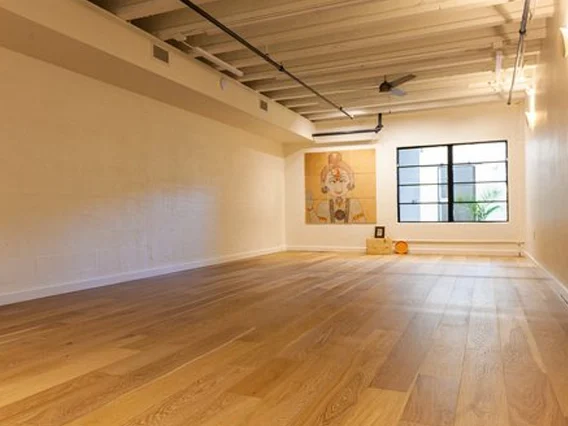 PtrBlt Miami Yoga Garage renovation photo of empty room in perspective, with wood floors and a window view at the end of the room