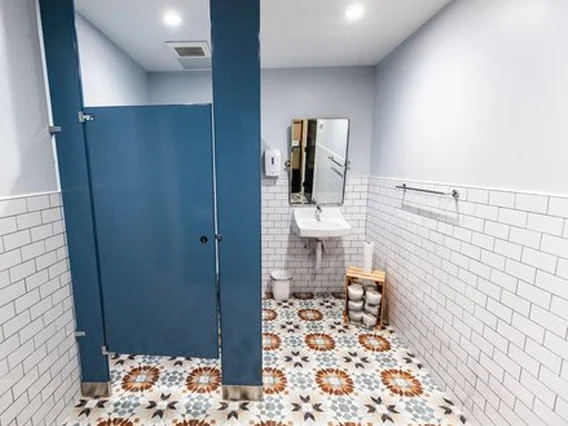 PtrBlt Miami Yoga Garage renovation photo of bathroom with statement floor tiles, subway wall tiles and a periwinkle blue stall