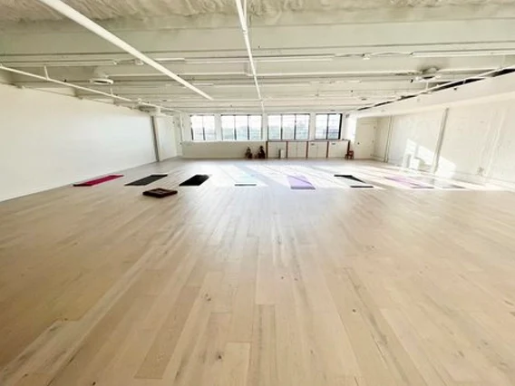 PtrBlt Miami Yoga Garage renovation photo of empty room in perspective, with light wood floors and sun shining in from windows.